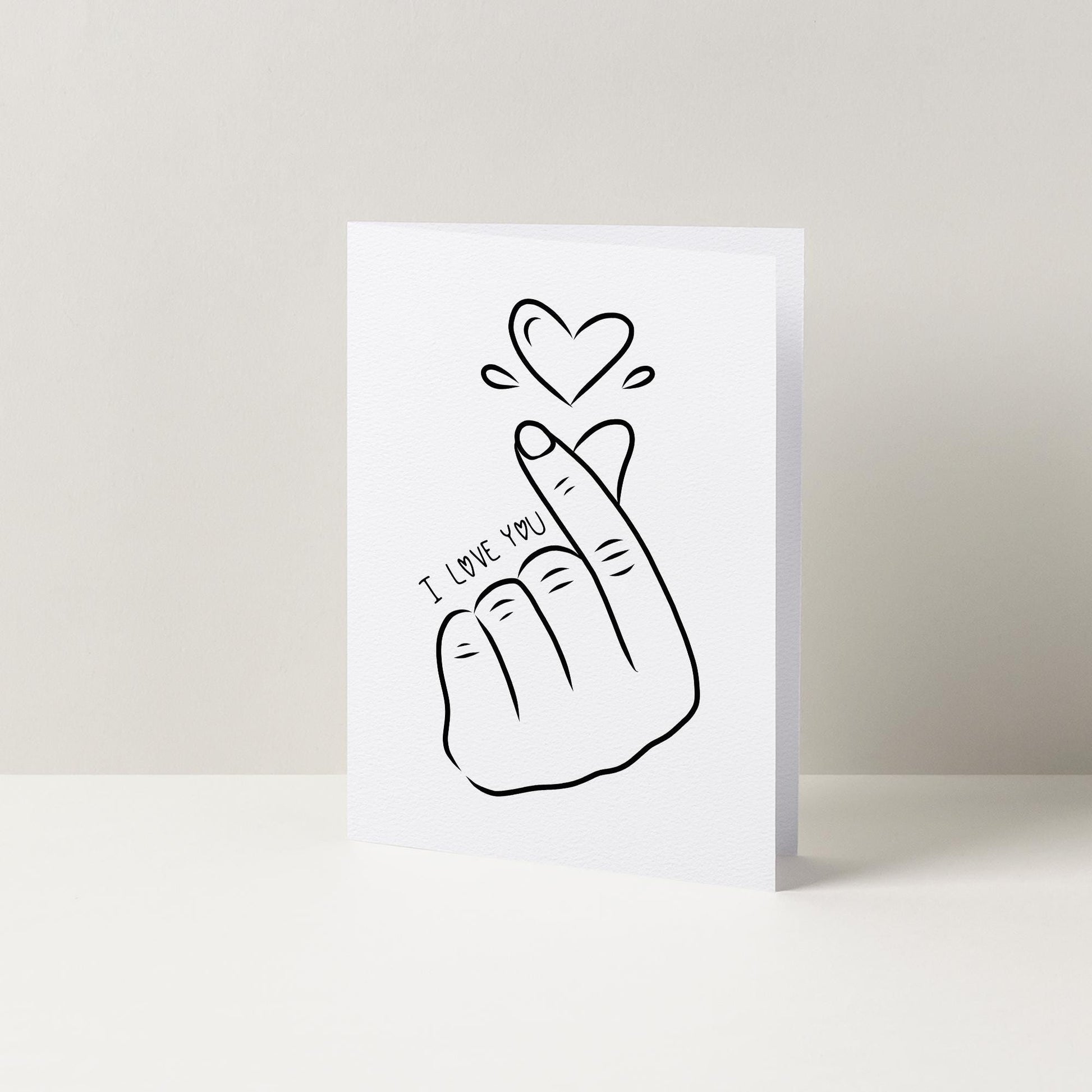 A simple black and white illustration of a hand forming a heart shape, accompanied by the text "I LOVE YOU" written below it.
